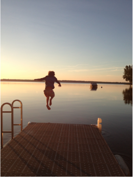 Child jumping off dock at sunset